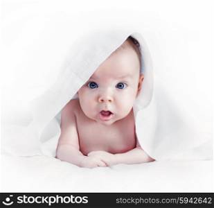 The surprised baby lying on white bed. Isolated on white