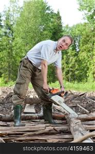 The surprised man with a chain saw in summer wood