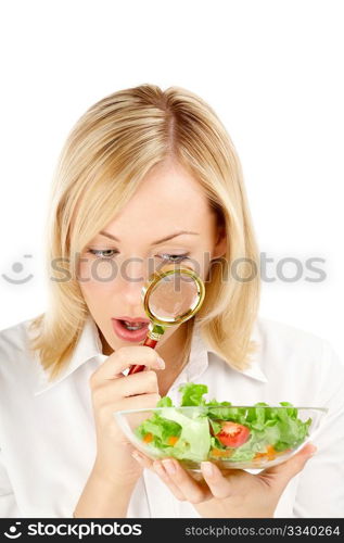 The surprised woman considers through a magnifier the vegetables, isolated