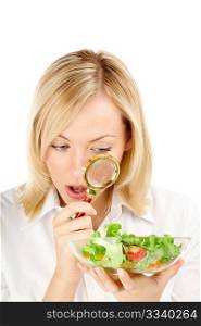 The surprised woman considers through a magnifier the vegetables, isolated