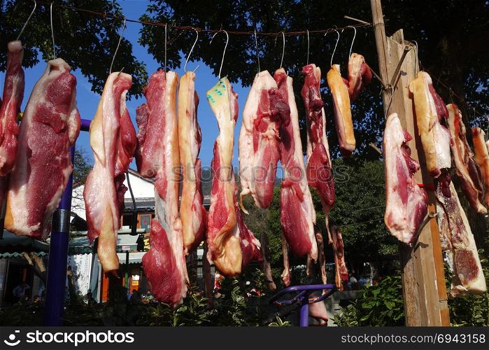 The suspended pieces of the meat drying outside on the sun