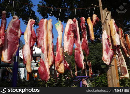 The suspended pieces of the meat drying outside on the sun