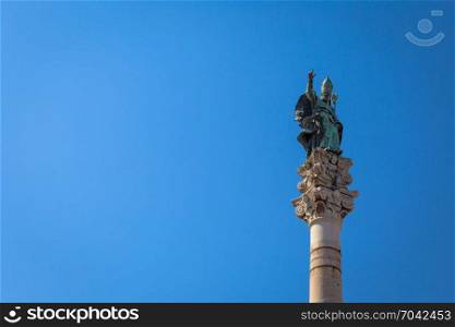 The symbol of Lecce town (Italy): Saint Oronzo (Sant&rsquo;Oronzo) posed on the column at the center of the main town Square. Blue backgroud with copy space.