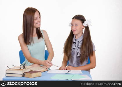 The teacher teaches the student sitting with him at the table