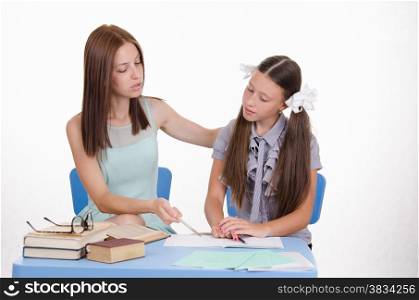 The teacher teaches the student sitting with him at the table