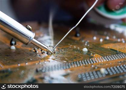 The technician repairing the computer mainboard by soldering