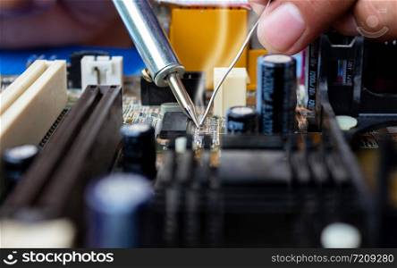 The technician repairing the computer mainboard by soldering