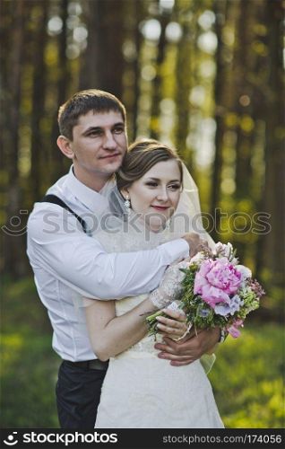 The tender embrace of the newlyweds in the woods.. Newlyweds hugging on the background of the forest 3964.