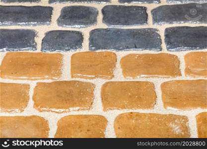 The texture of a fragment of a colored pavement of yellow and gray stone. Mosaic pattern. Close-up. Copy space.. Fragment of pavement from yellow and gray stone with selective focus.