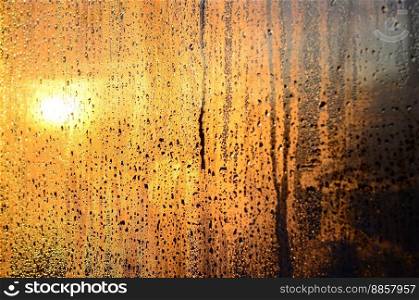 The texture of misted glass with a lot of drops and drips of condensation against the sunlight at dawn. Background image