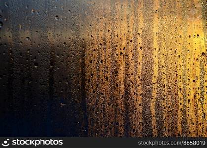 The texture of misted glass with a lot of drops and drips of condensation against the sunlight at dawn. Background image