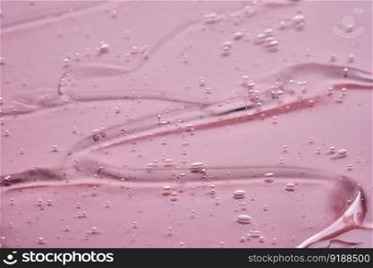 The texture of the cosmetic gel on a pink background.