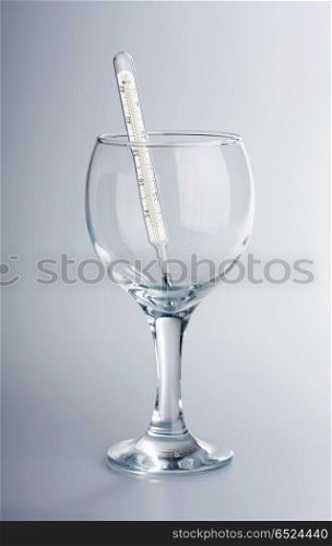 The thermometer in a glass glass on a white background. Medical imaginations
