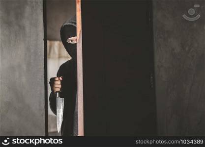 The thief holds a knife to open the house door for robbery.