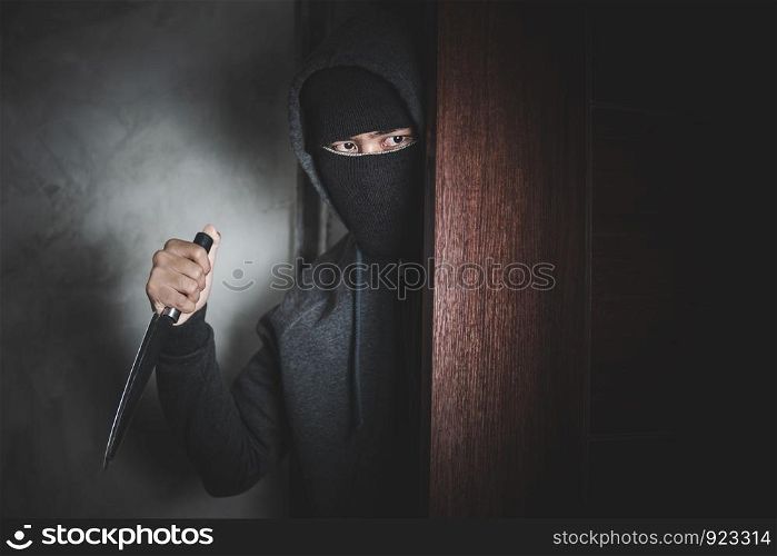 The thief holds a knife to open the house door for robbery.