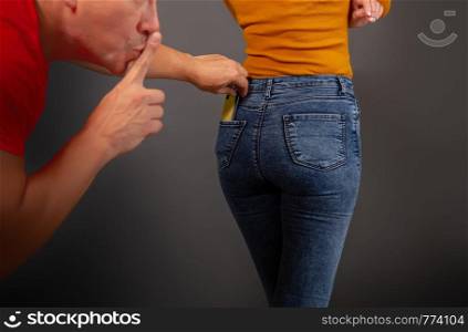 the thief stepping up imperceptibly behind the girl is trying to steal a smartphone from the back pocket of jeans. the thief steals the smartphone