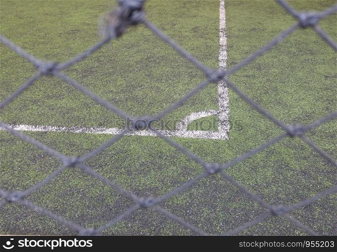 The thin mesh fence barrier between us and the corner football field, selective focus.