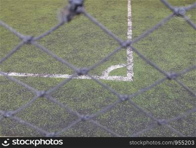 The thin mesh fence barrier between us and the corner football field, selective focus.