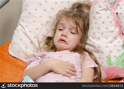 The three-year diseased girl lying in bed, Meria temperature thermometer, in a bad mood