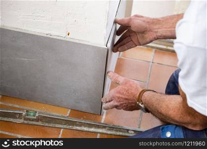 the tiler lays a ceramic tile on the wall