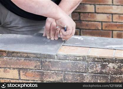 the tiler measures and puts marks to cut and lay a tile