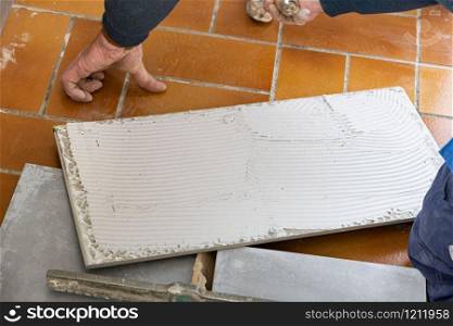 the tiler puts glue on the ceramic tile before laying it