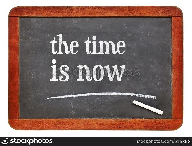 the time is now reminder - white chalk text on a vintage slate blackboard. blackboard