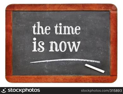 the time is now reminder - white chalk text on a vintage slate blackboard. blackboard