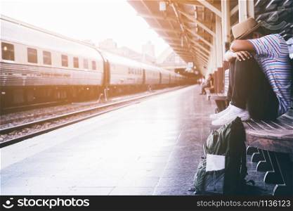 the tourist backpack man arrived late at the station. depressed and strain traveler sad sitting waiting at train station after mistakes a train makes wasting time in traveling.