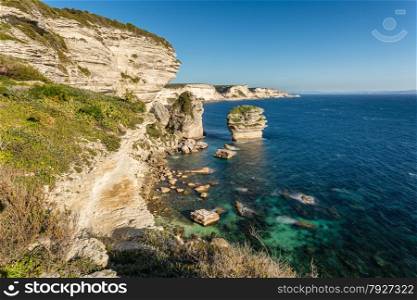 The towering white cliffs and stacks in the Mediteranean at Bonifacio in the south of Corsica with Sardinia in the background