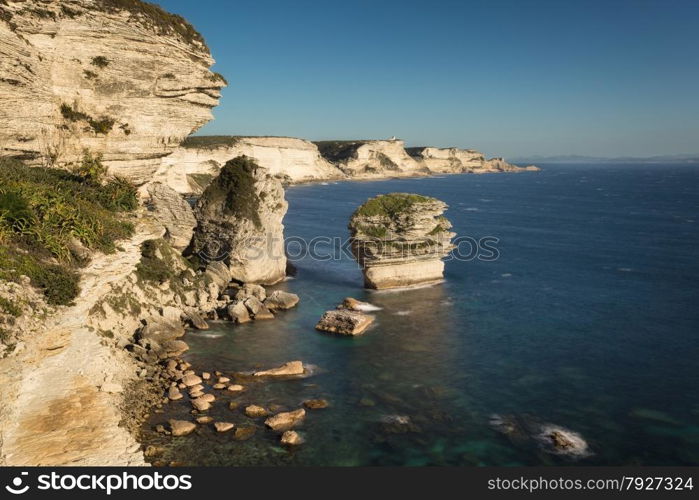 The towering white cliffs and stacks in the Mediteranean at Bonifacio in the south of Corsica with Sardinia in the background