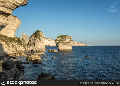 The towering white cliffs and stacks in the Mediteranean at Bonifacio in the south of Corsica with Sardinia in the background