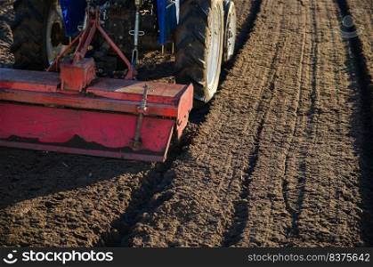 The tractor cultivator breaks up and mixes the soil, giving it softness and moisture for further cutting into rows. Small farms. Work in the agricultural industry. Agricultural machinery