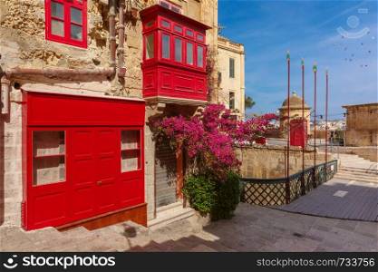 The traditional Maltese street with red phone box and building with colorful shutters and balconies at sunrise, Valletta, Capital city of Malta. Domes and roofs at sunset, Valletta , Malta