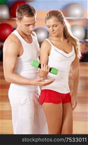 The trainer instructs the girl from dumbbells