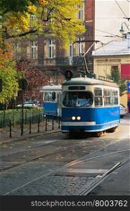 The tram is moving down the street, autumn-colored trees, the autumn sun