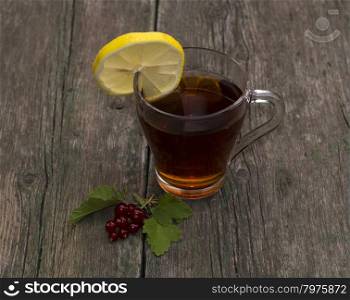 the transparent cup of tea with a lemon decorated with currant, a subject drinks