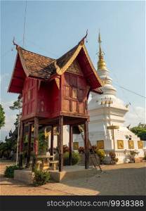 The tripitaka or hall for keeping the scriptures built from teak wood in northern art style. Holy tripitaka hall in front of the white pagoda.