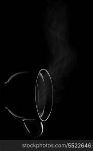The turned cup filled by steamy hot drink.