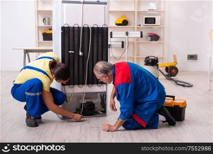 The two contractors repairing fridge at workshop. Two contractors repairing fridge at workshop