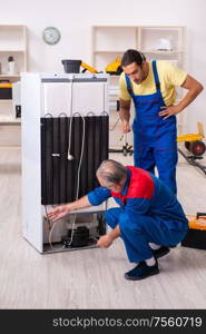 The two contractors repairing fridge at workshop. Two contractors repairing fridge at workshop