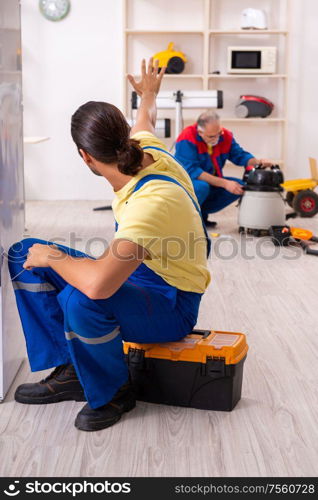 The two contractors repairing fridge at workshop. Two contractors repairing fridge at workshop