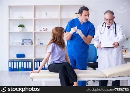 The two doctors examining young woman. Two doctors examining young woman