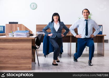 The two employees doing sport exercises in the office. Two employees doing sport exercises in the office