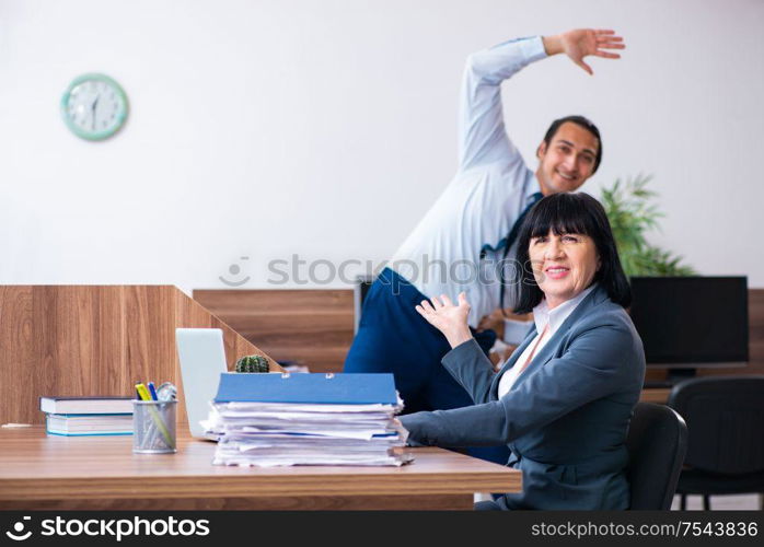 The two employees doing sport exercises in the office. Two employees doing sport exercises in the office