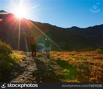 The two hikers in the mountains in the sun