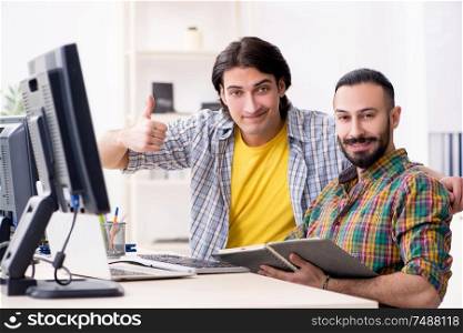 The two it specialists working in the office . Two it specialists working in the office