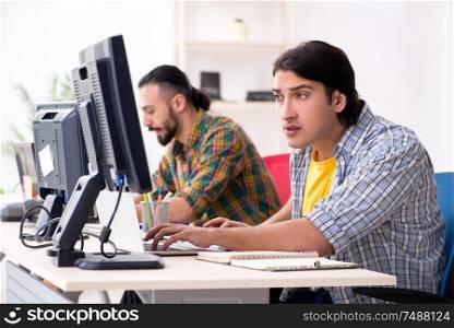 The two it specialists working in the office. Two it specialists working in the office