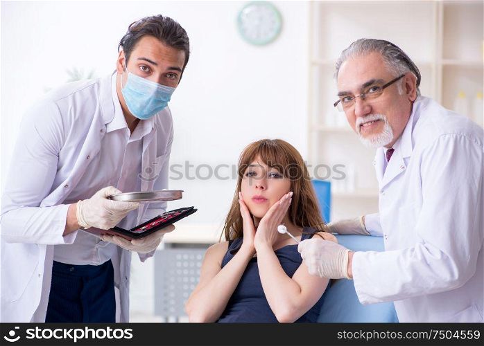 The two male doctors and young woman in plastic surgery concept. Two male doctors and young woman in plastic surgery concept