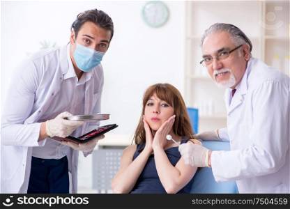 The two male doctors and young woman in plastic surgery concept. Two male doctors and young woman in plastic surgery concept